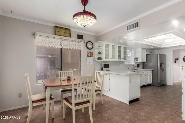 kitchen with sink, stainless steel fridge, ornamental molding, dark tile patterned floors, and white cabinetry