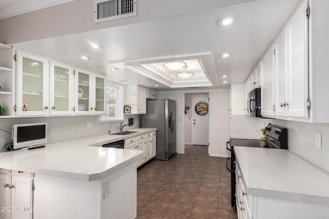 kitchen with white cabinetry, sink, kitchen peninsula, a tray ceiling, and black appliances