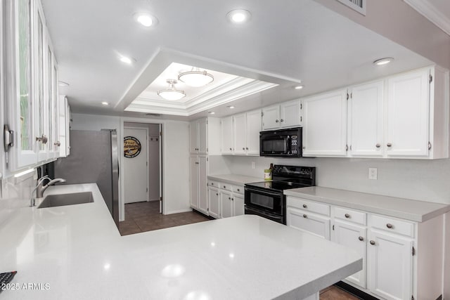 kitchen with kitchen peninsula, sink, white cabinets, and black appliances