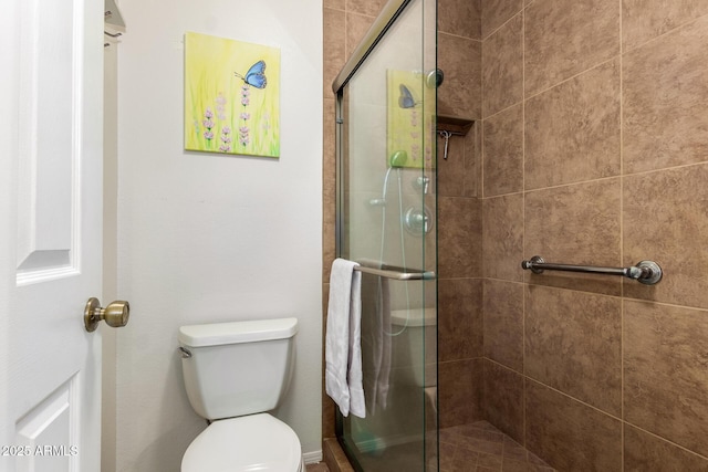 bathroom featuring toilet and a shower with shower door