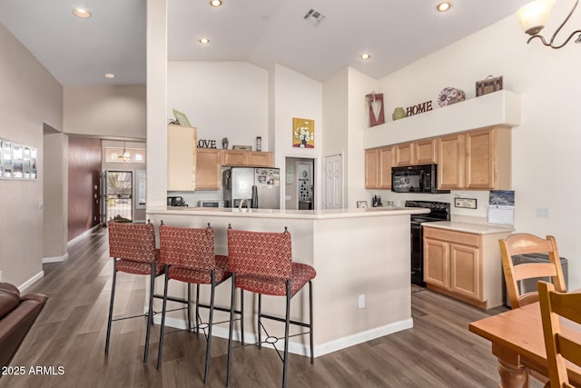 kitchen with high vaulted ceiling, black appliances, kitchen peninsula, and a kitchen bar