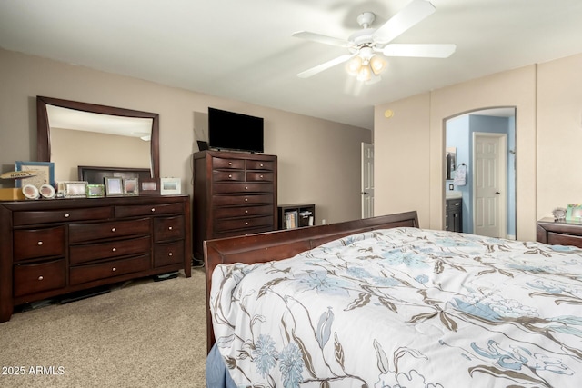 bedroom featuring ensuite bath, light colored carpet, and ceiling fan