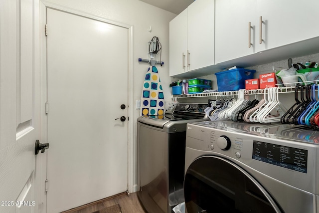 washroom featuring cabinets, wood-type flooring, and washing machine and dryer