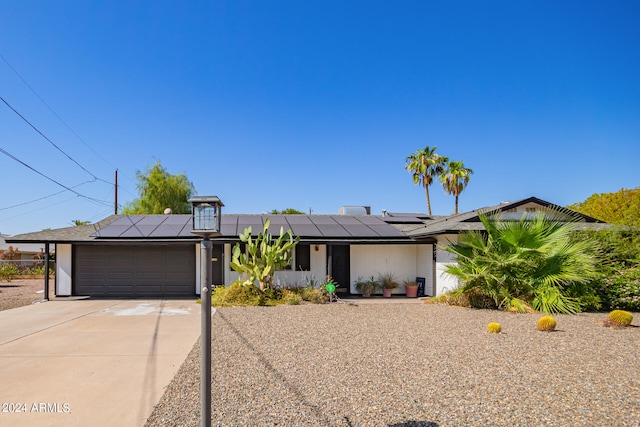 ranch-style home with solar panels and a garage