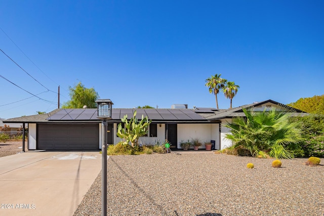 view of front of home with roof mounted solar panels, stucco siding, an attached garage, and concrete driveway