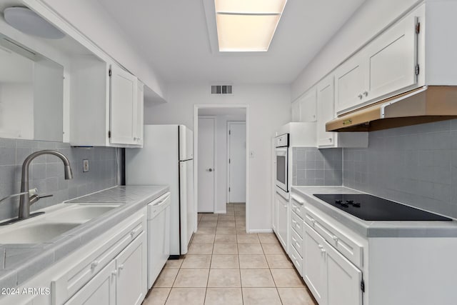 kitchen with white appliances, under cabinet range hood, a sink, visible vents, and white cabinets
