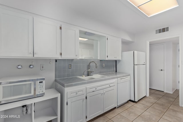 kitchen featuring visible vents, tile counters, white appliances, white cabinetry, and a sink