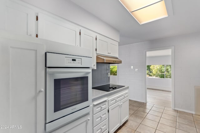 kitchen with white cabinetry, under cabinet range hood, black electric cooktop, and oven