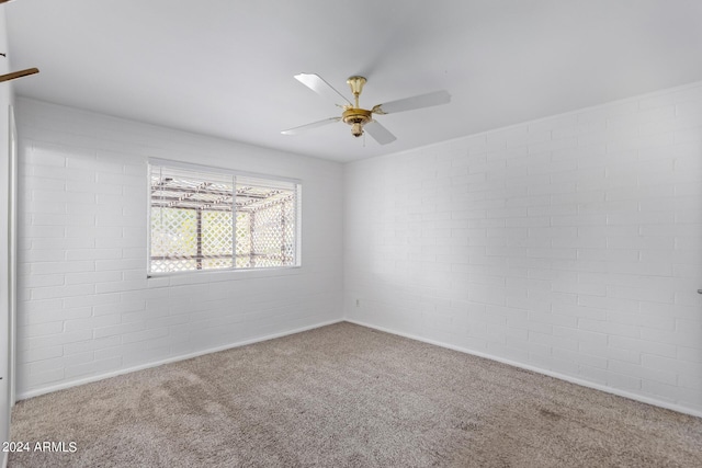 carpeted empty room featuring a ceiling fan and brick wall