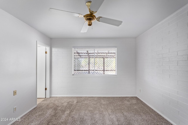 unfurnished room with carpet floors, brick wall, and a ceiling fan