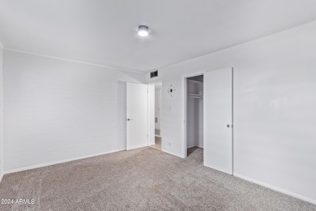 unfurnished bedroom featuring carpet floors, brick wall, a closet, and visible vents