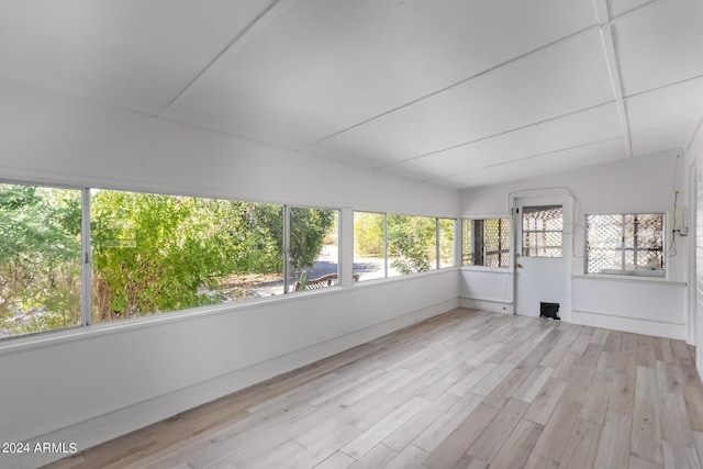 unfurnished sunroom featuring lofted ceiling, wood finished floors, and a deck