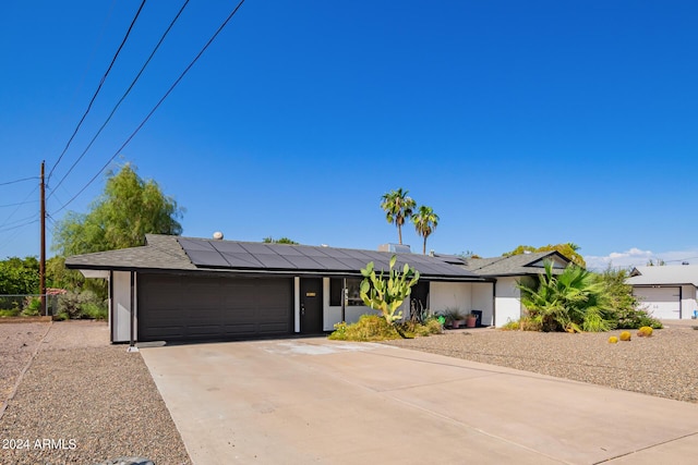 view of front of property featuring an attached garage, concrete driveway, and roof mounted solar panels