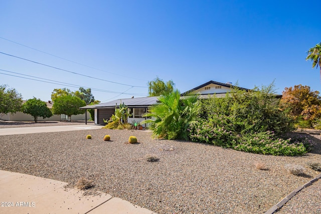 view of front facade featuring concrete driveway, solar panels, and an attached garage