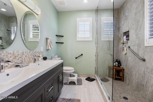 full bathroom with double vanity, tasteful backsplash, toilet, a tile shower, and a sink