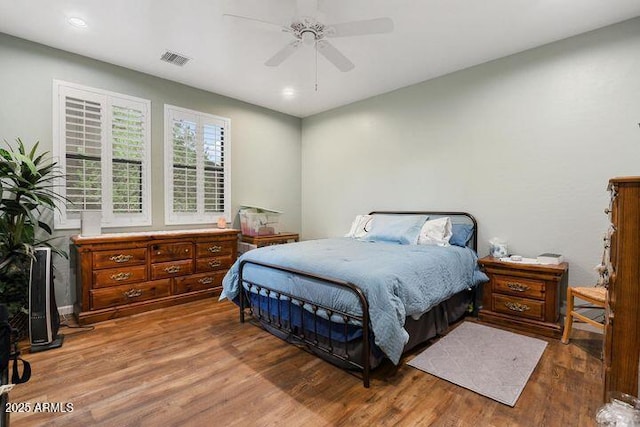 bedroom with ceiling fan, wood finished floors, and visible vents