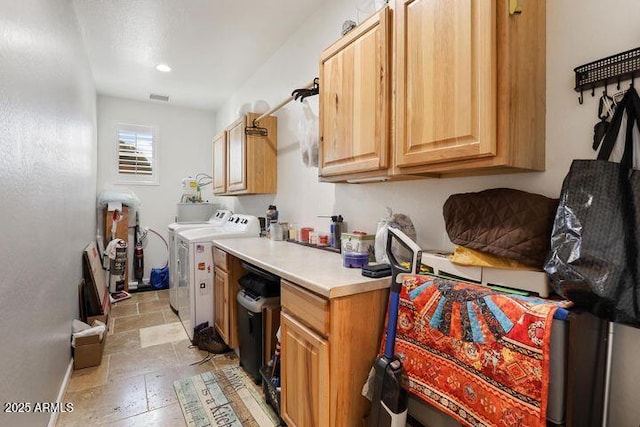 kitchen featuring stone tile flooring, light countertops, visible vents, separate washer and dryer, and baseboards