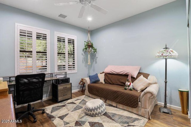 home office featuring a ceiling fan, visible vents, baseboards, and wood finished floors