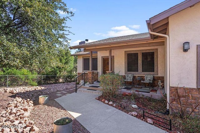 doorway to property featuring a porch, fence, and stucco siding