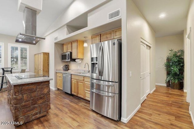 kitchen featuring stainless steel appliances, wood finished floors, a sink, visible vents, and island exhaust hood