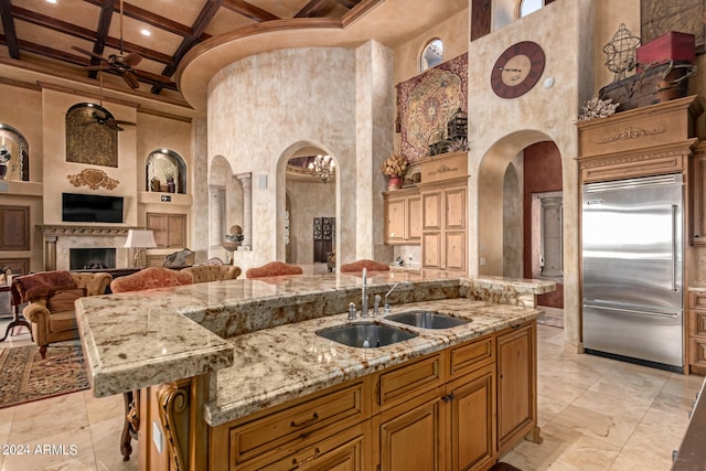 kitchen featuring ceiling fan, a towering ceiling, sink, coffered ceiling, and stainless steel built in fridge