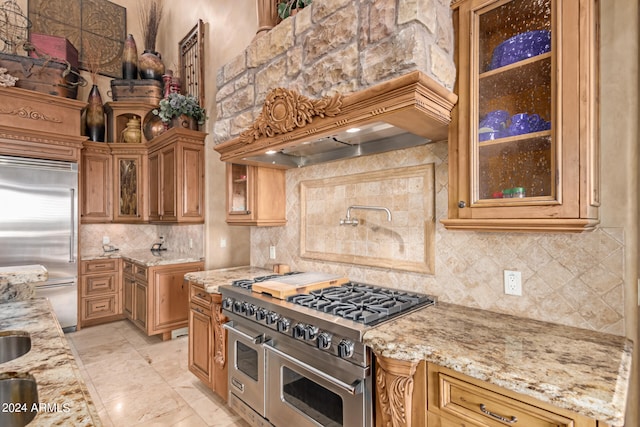 kitchen with light stone countertops, premium appliances, custom exhaust hood, backsplash, and light tile patterned flooring