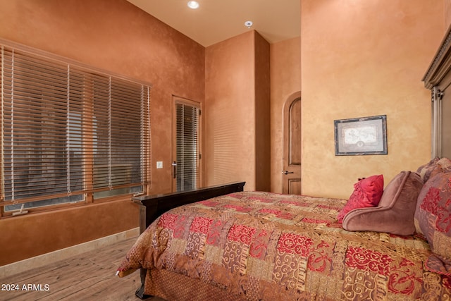 bedroom with hardwood / wood-style flooring and a high ceiling