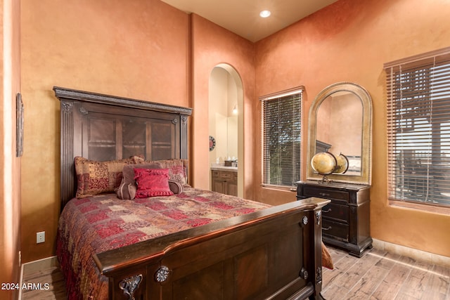 bedroom with light hardwood / wood-style flooring, ensuite bath, and multiple windows