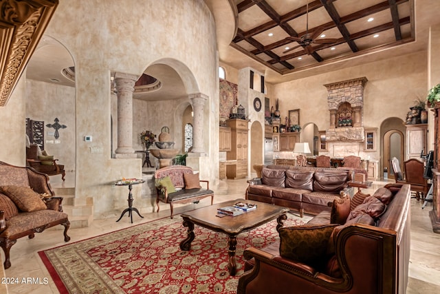 tiled living room featuring ornate columns, beam ceiling, ceiling fan, coffered ceiling, and a towering ceiling