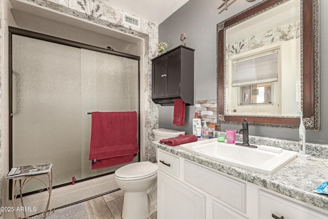 bathroom with visible vents, vanity, toilet, and a shower stall