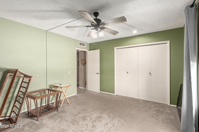 carpeted bedroom with a closet, visible vents, a textured ceiling, and ceiling fan