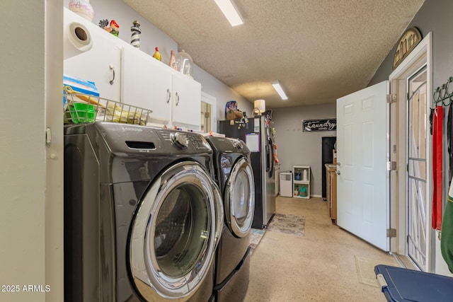 laundry room featuring cabinet space, a textured ceiling, and washing machine and clothes dryer