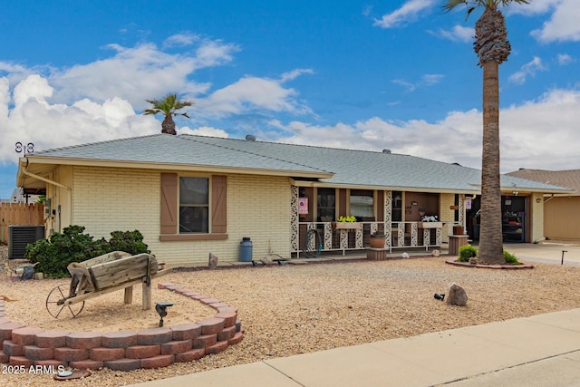 single story home with covered porch, brick siding, and central AC