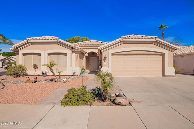 mediterranean / spanish house featuring concrete driveway, an attached garage, a tile roof, and stucco siding