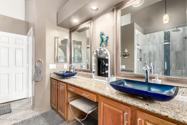 bathroom with double vanity, tile patterned floors, a sink, and tiled shower