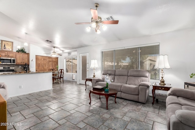 living room featuring plenty of natural light, visible vents, vaulted ceiling, and a ceiling fan