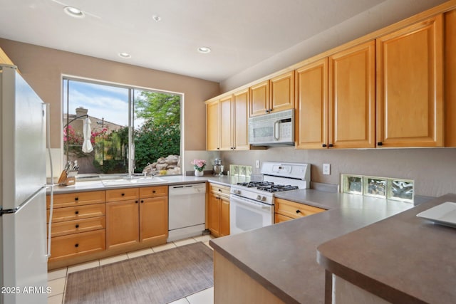 kitchen featuring a sink, light tile patterned flooring, white appliances, a peninsula, and recessed lighting