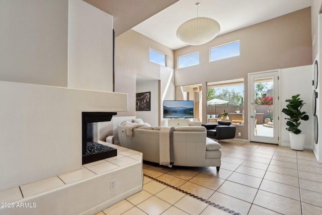 living room featuring a high ceiling, a multi sided fireplace, and light tile patterned floors
