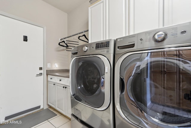 washroom with independent washer and dryer, light tile patterned floors, and cabinet space