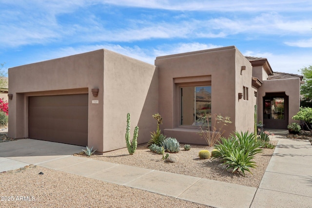 adobe home with an attached garage, concrete driveway, and stucco siding