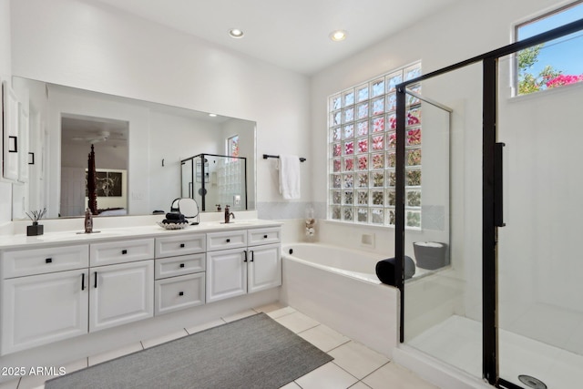 bathroom featuring plenty of natural light, a garden tub, double vanity, and a stall shower
