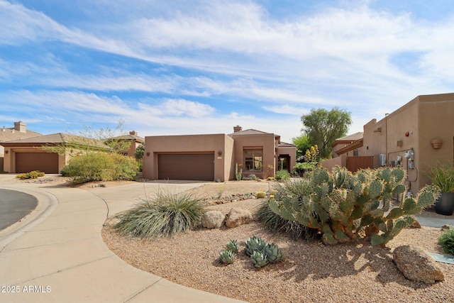 adobe home with an attached garage, concrete driveway, and stucco siding