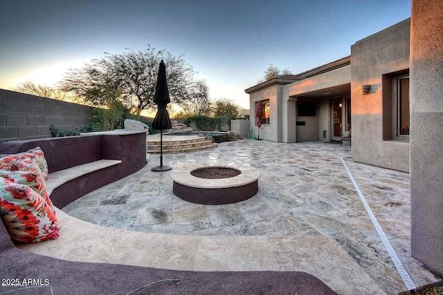 view of patio / terrace with a fenced backyard, a fire pit, and an in ground hot tub