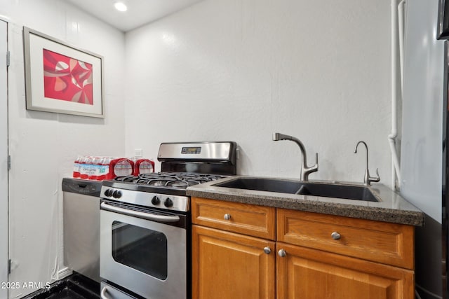 kitchen with a sink, recessed lighting, gas range, brown cabinets, and refrigerator