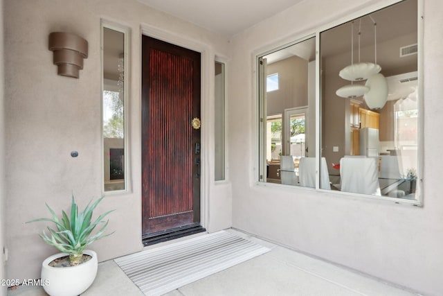 property entrance featuring visible vents and stucco siding
