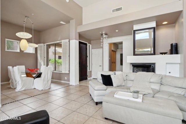 living area with baseboards, light tile patterned flooring, visible vents, and a fireplace