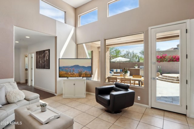 living room featuring baseboards, a high ceiling, and light tile patterned floors