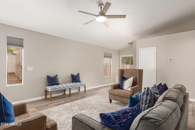 living area featuring vaulted ceiling, visible vents, plenty of natural light, and wood finished floors