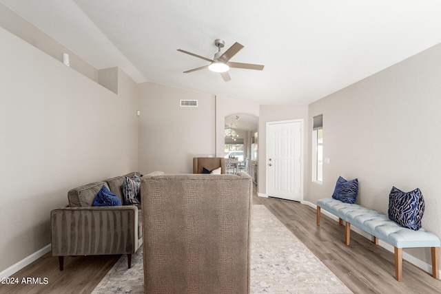 living room featuring arched walkways, lofted ceiling, visible vents, ceiling fan, and wood finished floors