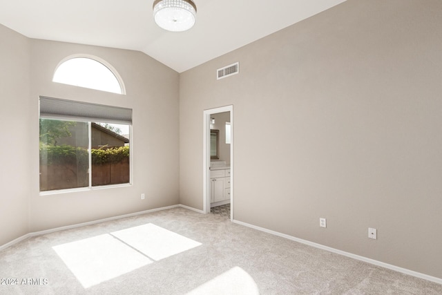 unfurnished room with light colored carpet, visible vents, lofted ceiling, and baseboards